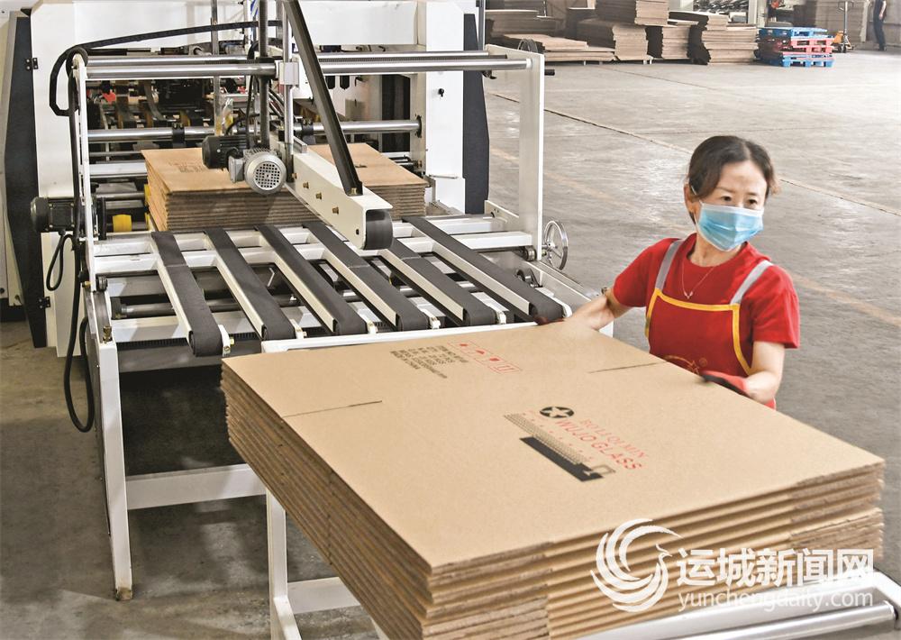8月31日,闻喜县宏伟玻璃器皿包装厂车间工人在纸箱包装生产线上作业.